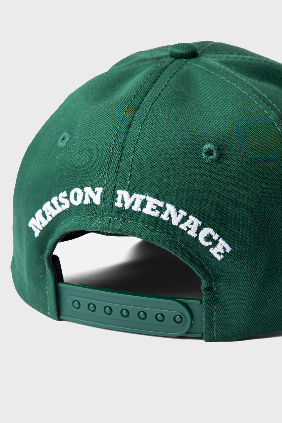 The Maison Menace Signature Hat in Cactus is a green baseball cap with MAISON MENACE embroidered in white on the back and an adjustable snap strap for a perfect fit.