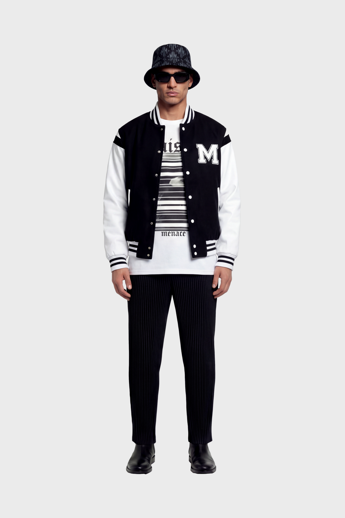 Person wearing a black and white varsity jacket with a white long-sleeve t-shirt with black text and graphics on front underneath against white background