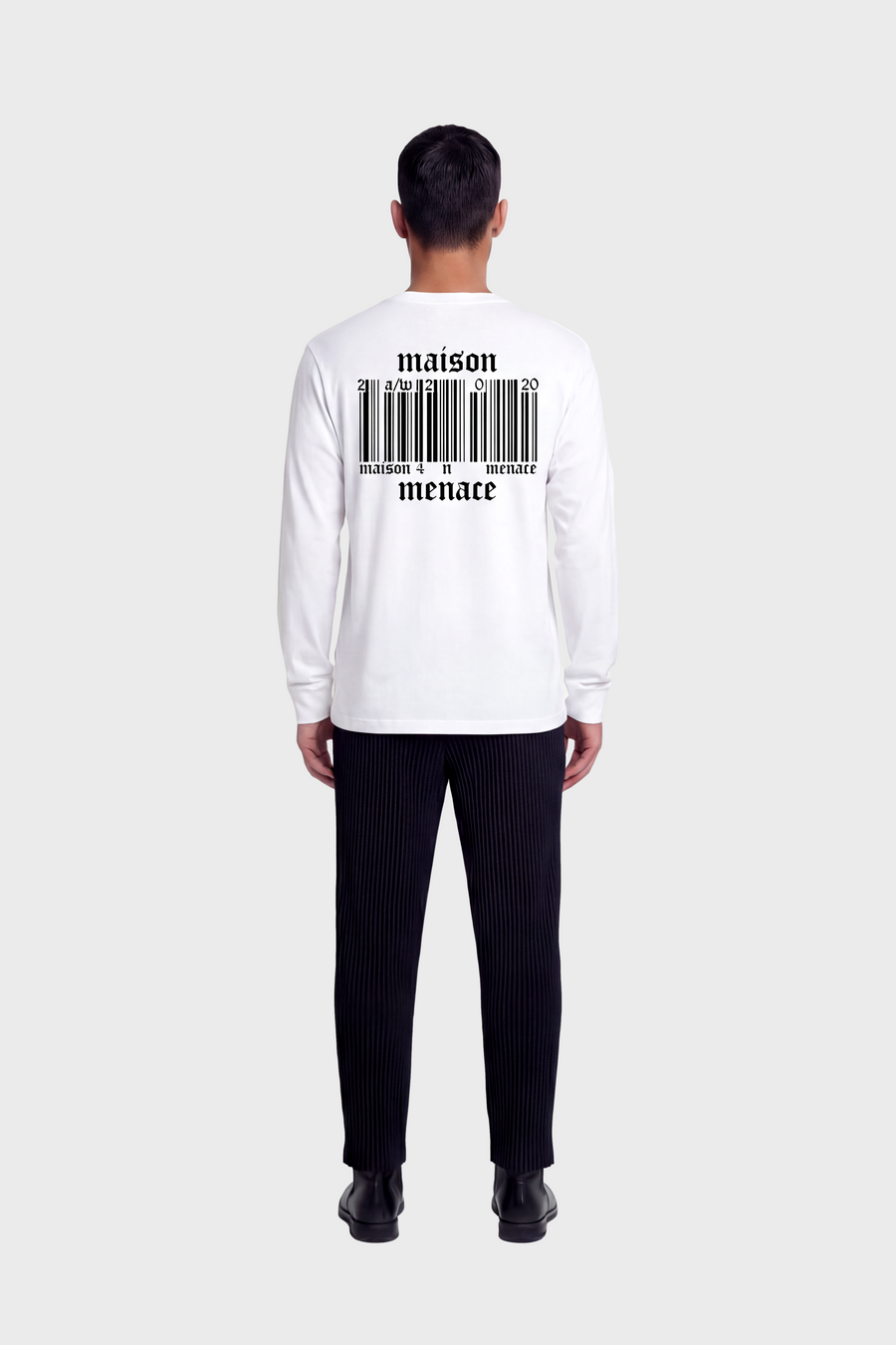 Man wearing a white long-sleeve shirt with 'maison menace barcode' design on the back, standing against a white background.