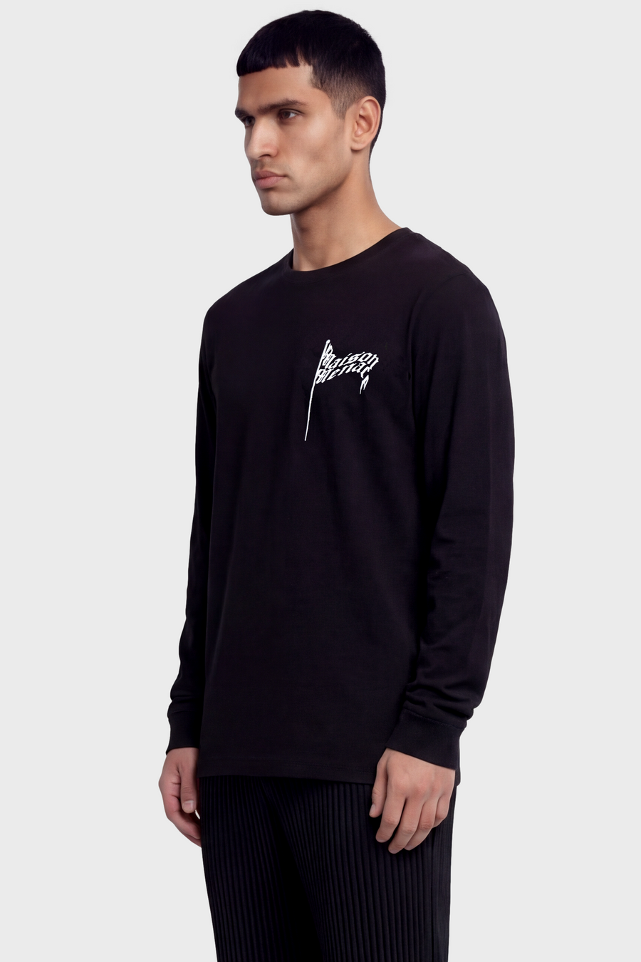 Man wearing a black long-sleeve t-shirt with a flag logo on a light gray background