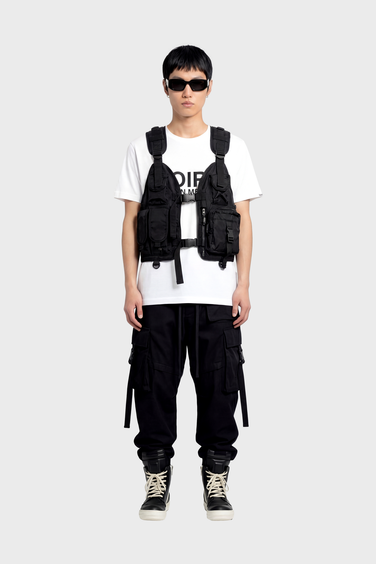 Person wearing a black tactical vest over a white t-shirt with visible branding on a white background