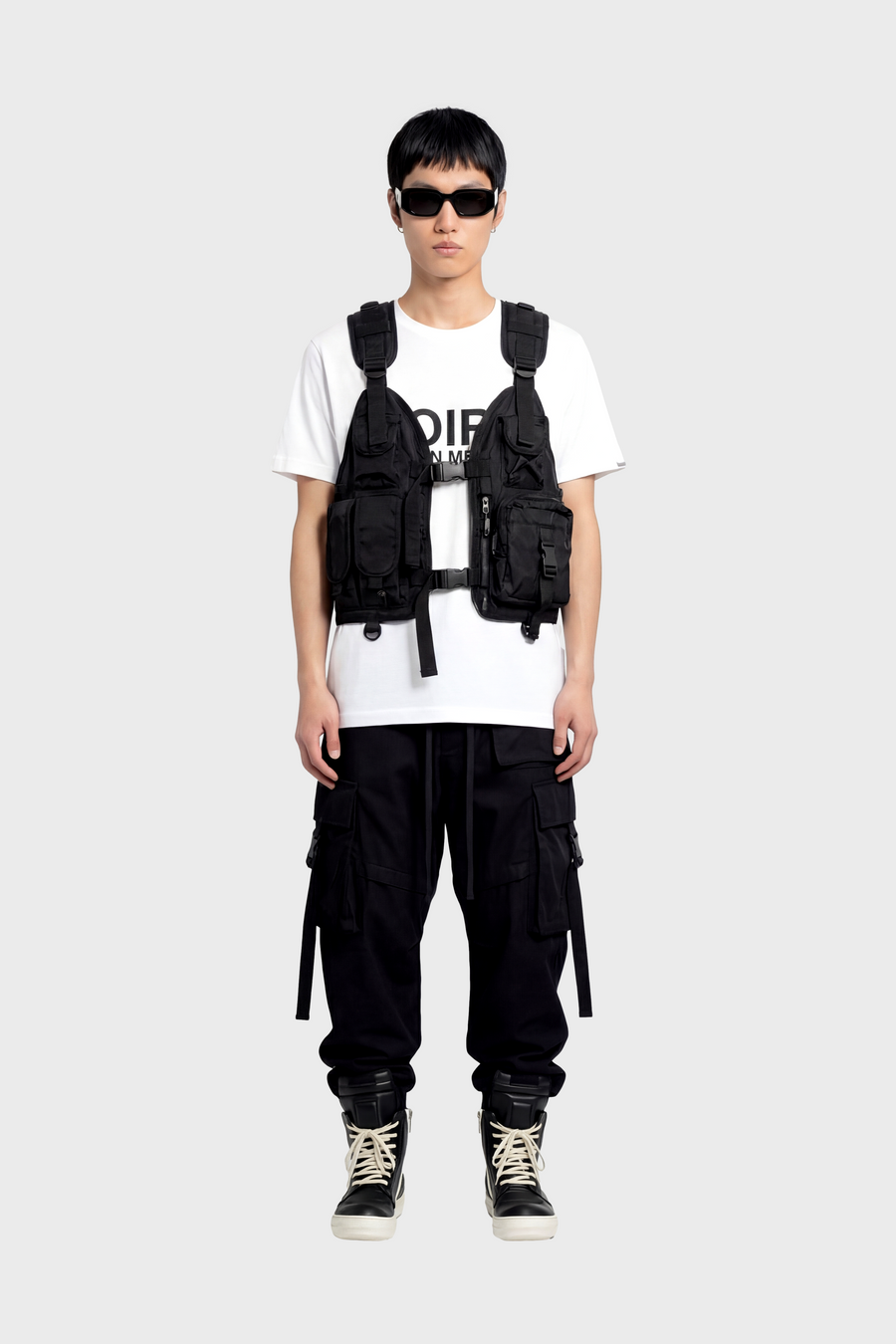 Person wearing a black tactical vest over a white t-shirt with visible branding on a white background